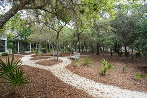 Un sentier qui traverse un espace aménagé comme un parc, avec des bancs et des arbres.