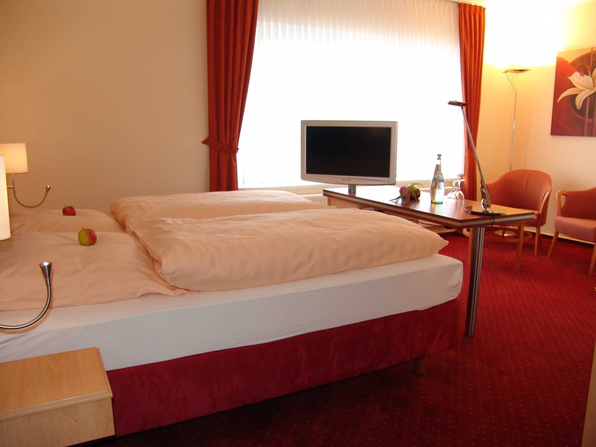 Ein Hotelzimmer mit einem Bett, einem Schreibtisch, einem Stuhl, einem Fernseher und einer Lampe.