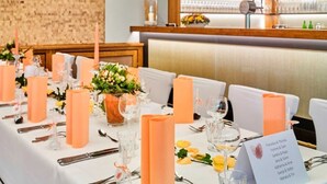 Un restaurante con mesas dispuestas para comer, una zona de bar con botellas y un cartel con nombres.