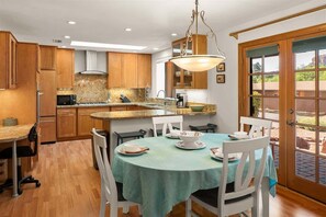 Una cocina con armarios de madera, encimera de granito y un comedor con mesa lista para cuatro.