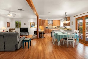 Una sala moderna con sofá, televisión y comedor con sillas y una mesa.