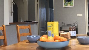 Ett matbord med en skål med apelsiner, en gul behållare och en burk med jordnötssmör.