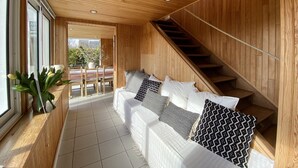 A cozy room with a wooden ceiling, a sofa with patterned cushions, a staircase, and a view of the outdoors. - wood-panelled sailor's cottage a stone's throw from the port (Bénodet)