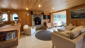 A cozy living room with a stone fireplace, wooden ceiling, and large windows. - wood-panelled sailor's cottage a stone's throw from the port (Bénodet)