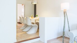 Ein moderner Essbereich mit weißen Stühlen und einem Tisch, einer Hängelampe und einer Stehlampe.