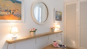 Ein Zimmer mit einem hölzernen Regal, das Lampen, Blumentöpfe und einen Spiegel beherbergt.
