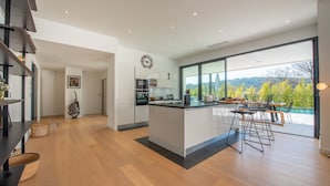 Una cocina moderna con una isla grande, electrodomésticos integrados y vistas a un paisaje exuberante.