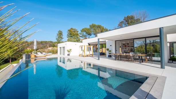 Una casa moderna con piscina, mobiliario exterior y vistas del paisaje circundante.