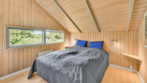 Une chambre à coucher avec un lit, deux oreillers, une fenêtre et des murs en bois.