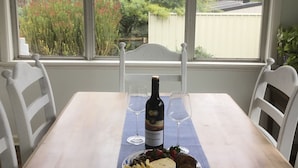 Una mesa de comedor con una botella de vino, dos copas de vino y un plato de comida.