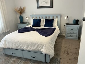 A bedroom with a bed, two nightstands, a dresser, a vase with dried flowers, and a framed picture on the wall. - Cosy Country Cottage in the Pyrenees( Pet Friendly.)  (Avoca)