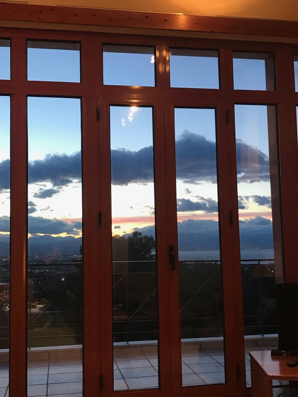 A view through a set of glass doors with a cityscape and mountains in the background.