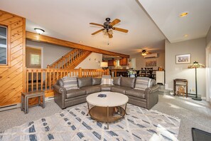 A modern living room with a sectional sofa, a coffee table, and a ceiling fan.