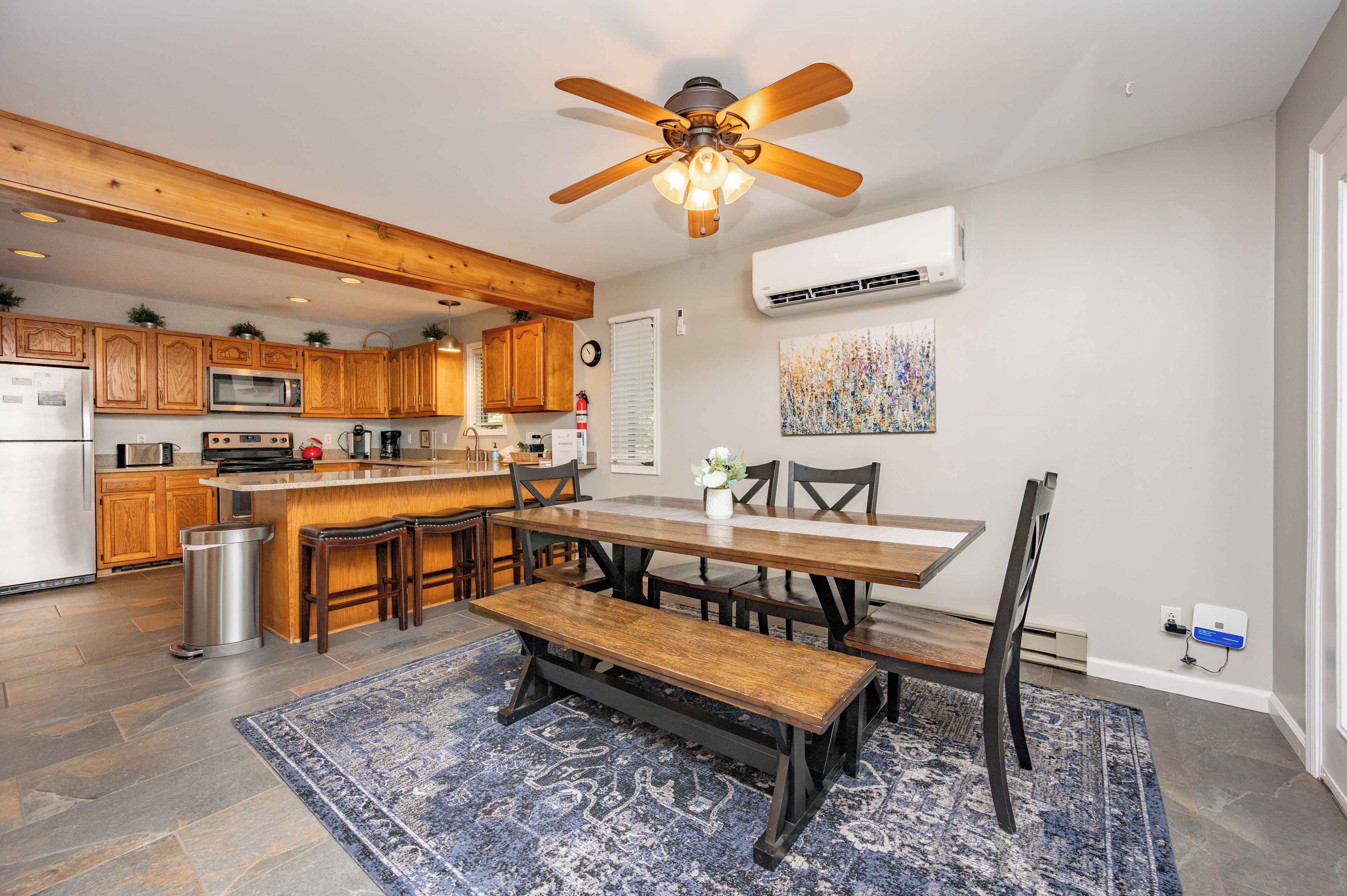A modern kitchen with wooden cabinets, a central island, and a dining area with a bench and chairs.