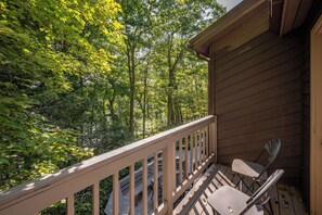 A wooden deck with a railing, overlooking a forested area.