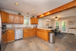 A modern kitchen with wooden cabinets, a dishwasher, and a dining area with a table and chairs.