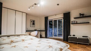 Une chambre à coucher comprenant un lit, un bureau, une chaise, une armoire et une fenêtre avec des rideaux.