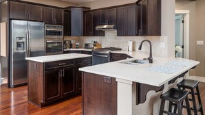 Una cocina moderna con gabinetes de madera oscura, electrodomésticos de acero inoxidable y una isla grande con taburetes de bar.