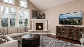 Una sala de estar con chimenea, sofá, mesa de centro y televisor.