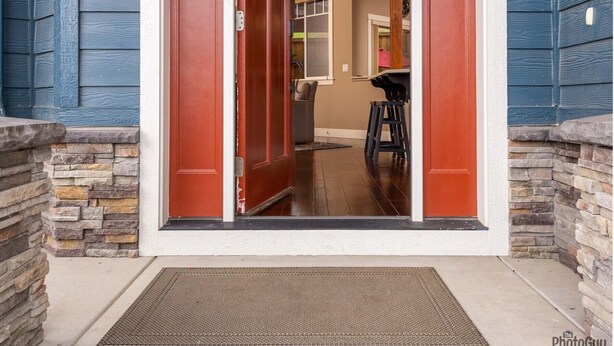 Entrada de una casa con puerta roja, escalones de piedra y cocina a la vista.