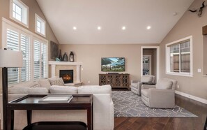 A spacious living room with a fireplace, comfortable seating, and a large TV.