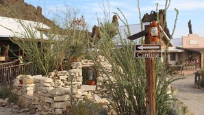 Paredão rústico de pedra com uma placa de madeira indicando Cantina.