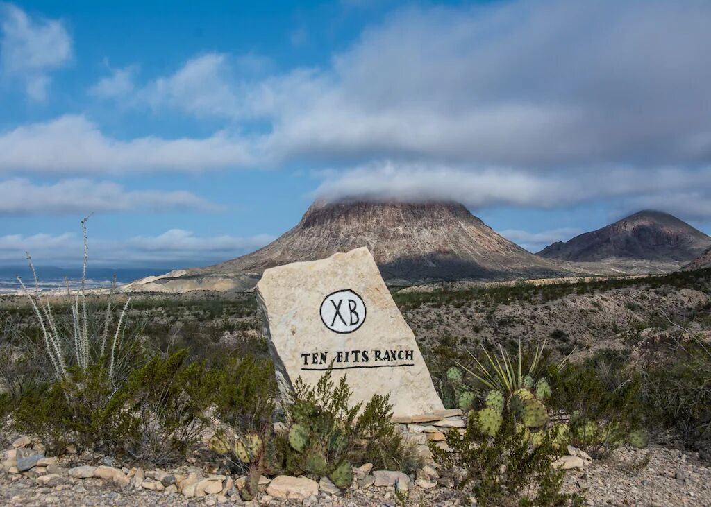 Ein Schild für Ten Bits Ranch, mit einem Berg im Hintergrund.