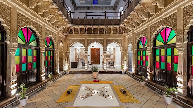 Un interior ornamentado con una zona de estar central, detalles arquitectónicos intrincados y vista al acceso.