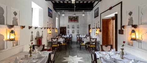A dining area with tables set for service, a star-patterned floor, and wall-mounted lanterns.