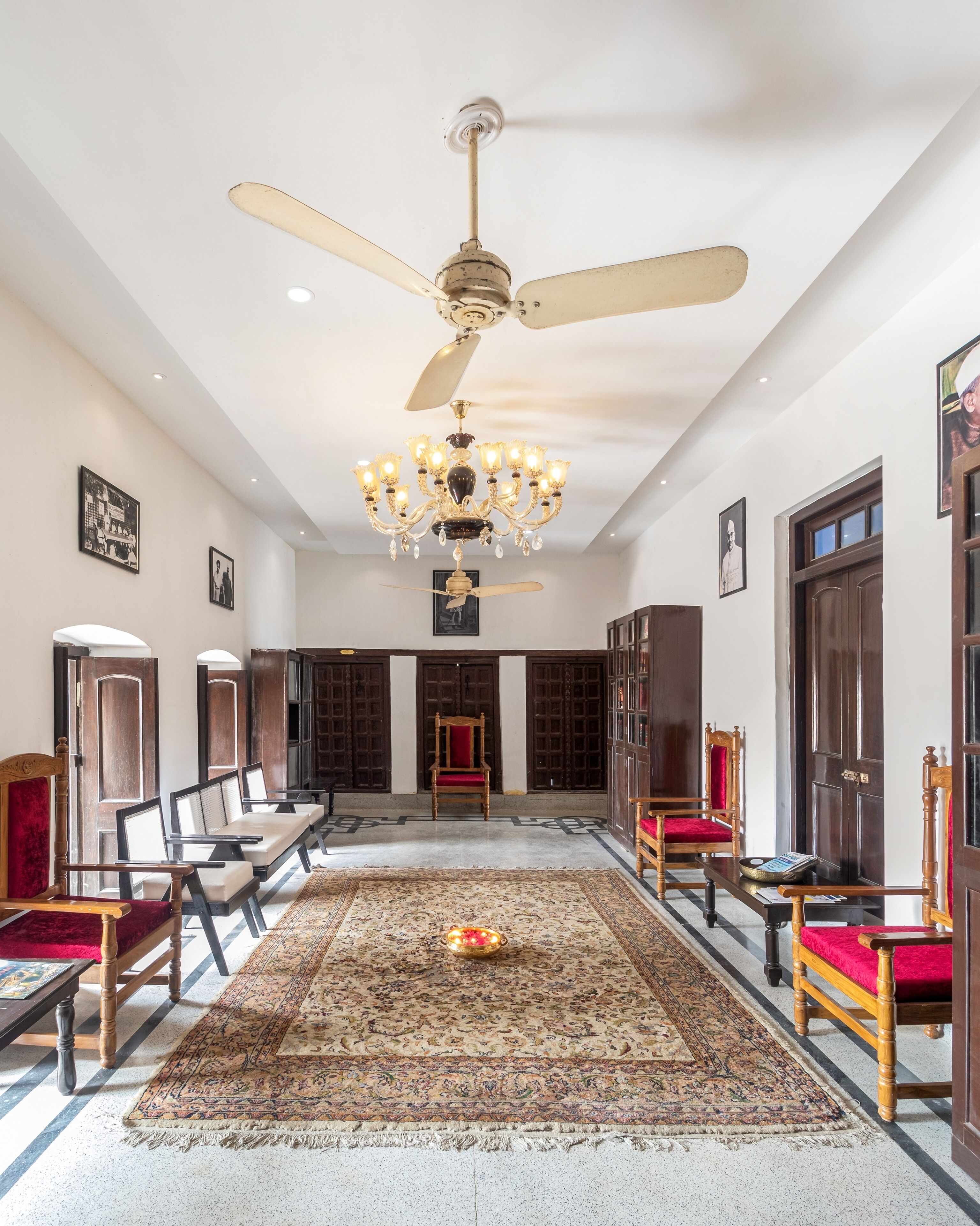 A spacious room with a chandelier, ceiling fans, and a patterned rug.