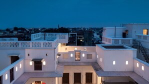 Un patio central con una fuente, rodeado por edificios blancos con varios balcones y ventanas.