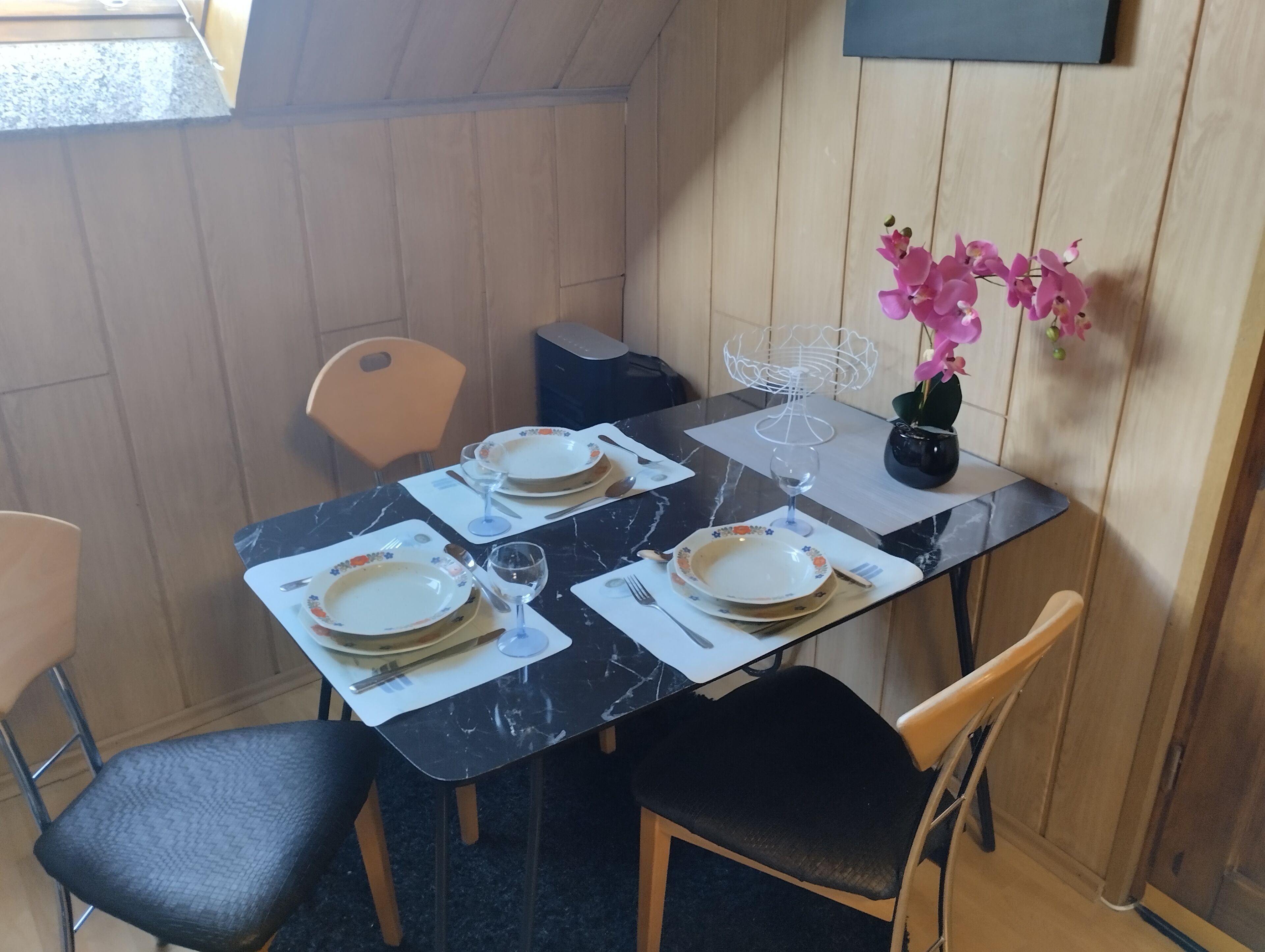 Une table à manger dressée avec des assiettes, des couverts et un verre d’eau.