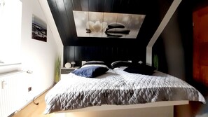 A modern bedroom with a bed, a nightstand, and a wall-mounted artwork. - Ferienwohnung "Am Vulkanpfad" (Ettringen)