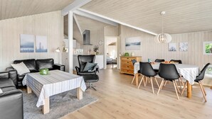 Ein modernes Wohnzimmer mit einer Couch, einem Esstisch mit Stühlen und einem durch einen offenen Durchgang einsehbaren Küchenbereich.