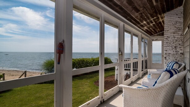 A covered outdoor seating area with a view of the sea, a wooden ceiling, and a white brick wall. - Rare! Private Beachfront House in Madison CT - Sleeps 8 - Last Min Availability (Madison)