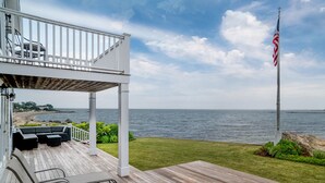 A wooden deck with outdoor seating, a view of the ocean, and an American flag. - Rare! Private Beachfront House in Madison CT - Sleeps 8 - Last Min Availability (Madison)