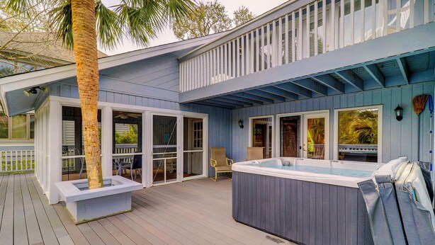 Een terras met een jacuzzi, stoelen en een palmboom.