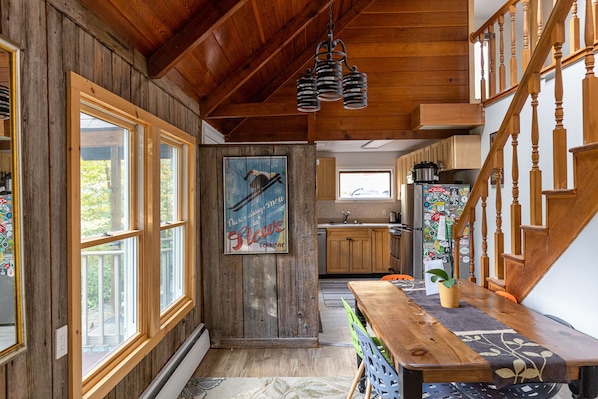 Cozy cabin-style interior with a wooden staircase, kitchen, and dining area.