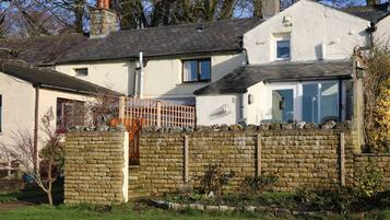 A two-story house with a stone wall and a wooden fence.
