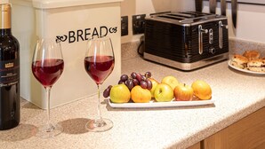 A kitchen with hanging pots, a bread box, a toaster, and a plate of fruit and wine glasses. - Ingleton 2-bed Cottage, Sleeps 4, Pet Ok & Parking (Carnforth)