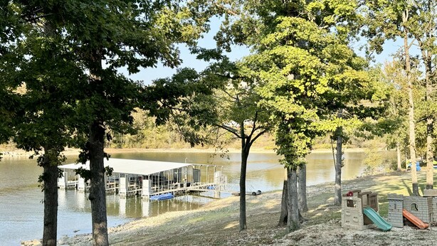Ein Park am Seeufer mit Steg, Spielplatz und Bäumen.
