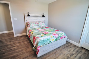 A bedroom with a bed, wooden headboard, and a floral bedspread. - PINK FLAMINGO, 3BD/2BA W/FENCED IN BACKYARD IN QUIET NEIGHBORHOOD! COMMUNITY POOL! (Mexico Beach)