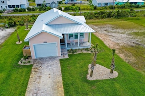 A single-story house with a garage, a covered porch, and a well-maintained lawn. - PINK FLAMINGO, 3BD/2BA W/FENCED IN BACKYARD IN QUIET NEIGHBORHOOD! COMMUNITY POOL! (Mexico Beach)