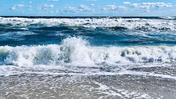 Une plage où les vagues se brisent sur le rivage sous un ciel dégagé.