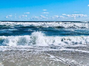 Una playa con olas rompiendo sobre la orilla bajo un cielo despejado.
