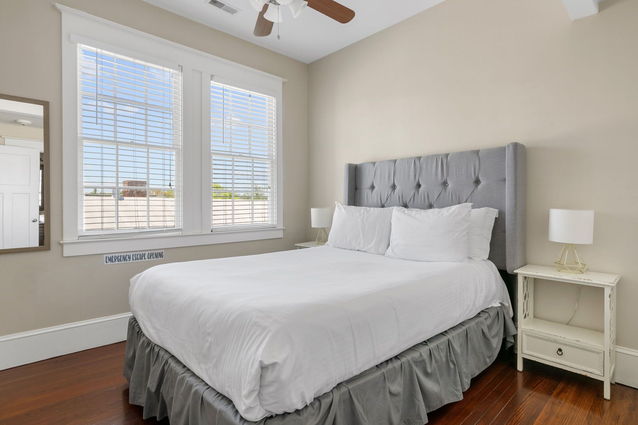 Une chambre à coucher avec un grand lit, une table de chevet et un ventilateur de plafond.