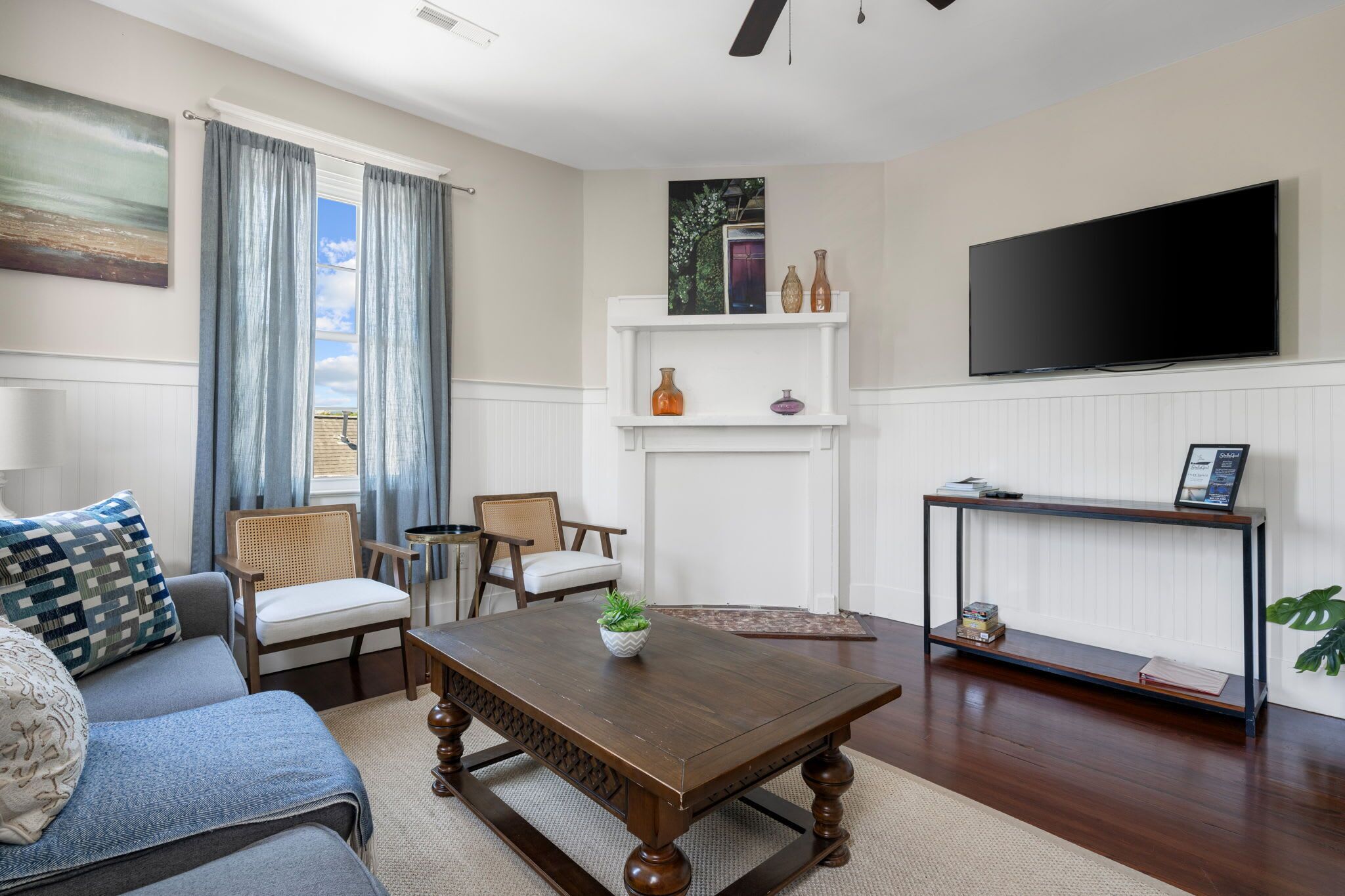 A living room with a sofa, chairs, a coffee table, a TV, and a fireplace.