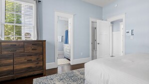 Een slaapkamer met een groot bed, een houten dressoir en een inloopkast.