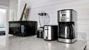 A kitchen with a microwave, toaster, blender, and coffee maker on a marble countertop. - The Oyster Suite | Walk to King + Cannon Green (Charleston)