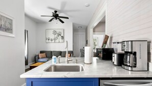 A modern kitchen with a marble countertop, stainless steel appliances, and blue cabinetry. - The Oyster Suite | Walk to King + Cannon Green (Charleston)